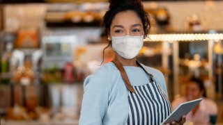 FILE - A waitress working at a restaurant wearing a face mask to avoid the spread of coronavirus.