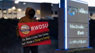 An RWDSU union rep holds a sign outside the Amazon fulfillment warehouse at the center of a unionization drive on March 29, 2021 in Bessemer, Alabama.