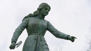 A statue of Hannah Duston, dated 1879, stands in the Grand Army of the Republic Park, Wednesday, April 28, 2021, in Haverhill, Mass., meant to honor the English colonist who, legend has it, slaughtered her Native American captors after the gruesome killing of her baby.
