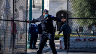 A Capitol Hill police officer tends to the reinforced gate at the Capitol on April 3, 2021.