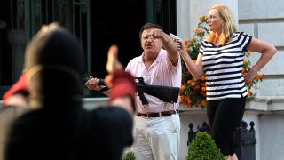 Armed homeowners Mark T. and Patricia N. McCloskey stand in front their house as they confront protesters marching to St. Louis Mayor Lyda Krewson's house on June 28, 2020.