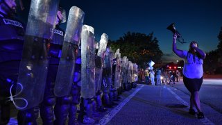 A protester is seen as police officers stand guard during protest against police brutality and the arrest of two brothers Ricky and Travis Price in Rock Hill, South Carolina, United States on June 24, 2021.