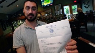 David Culhane, owner of the White Mountain Tavern, holds up a November 2020 letter from the N.H. Attorney General's office, notifying that his business was in violation, and also fined, after breaking an emergency order, July 13, 2021, in Lincoln, New Hampshire.