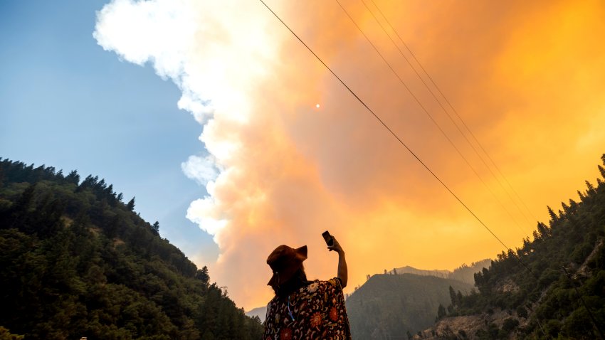 Jessica Bell takes a video as the Dixie Fire burns along Highway 70 in Plumas National Forest, Calif., on Friday, July 16, 2021. (AP Photo/Noah Berger)