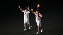 Torchbearers carry the Olympic torch as they enter the Olympic Stadium during the opening ceremony of the Tokyo 2020 Olympic Games, in Tokyo, on July 23, 2021.