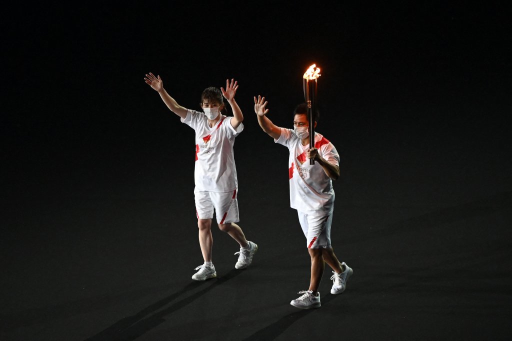 Torchbearers carry the Olympic torch as they enter the Olympic Stadium during the opening ceremony of the Tokyo 2020 Olympic Games, in Tokyo, on July 23, 2021.