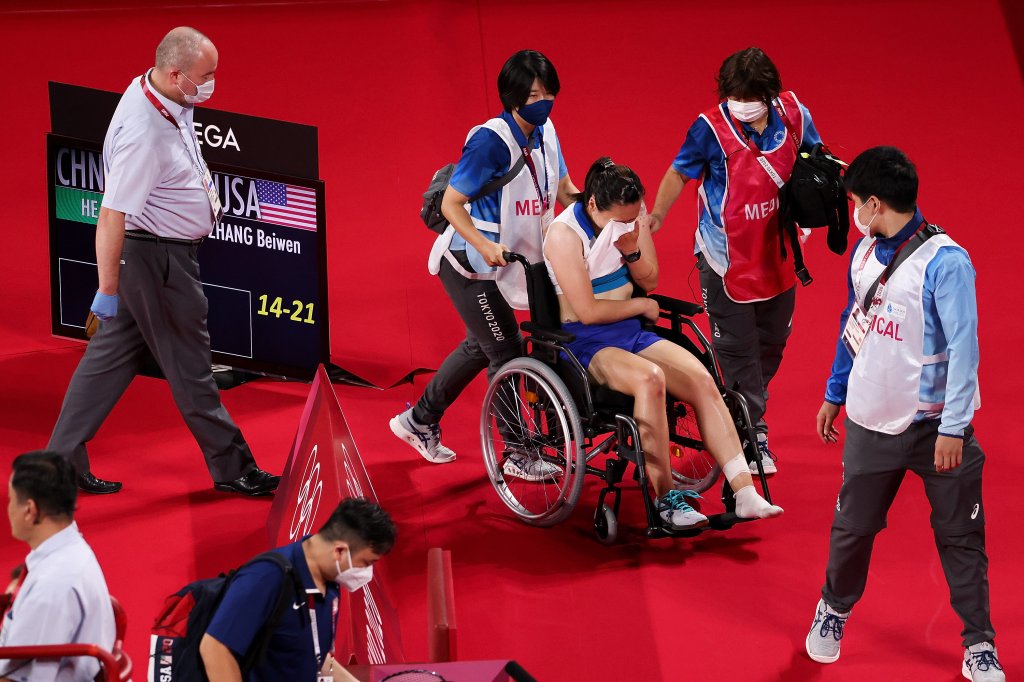 Beiwen Zhang (in wheelchair) of Team United States reacts after suffered a match-ending injury