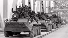 Soviet Army soldiers wave their hands as their last detachment crosses a bridge on the border between Afghanistan and then Soviet Uzbekistan near the Uzbek town of Termez, Feb. 15, 1989.