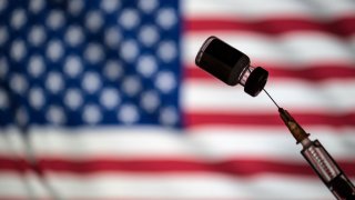 POLAND – 2021/01/24: In this photo illustration a vial of COVID-19 vaccine and a medical syringe displayed over an American flag. (Photo Illustration by Vito Corleone/SOPA Images/LightRocket via Getty Images)