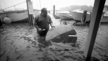 Kevin Murphy, owner of Shuckers Restaurant, tries to save a table as his restaurant floods during Hurricane Bob in Woods Hole, Mass., on Aug. 19, 1991.
