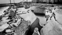 Pieces of a stone wall, each weighing seven tons, that were used to protect Menauhant Road in Falmouth against storm surges were thrown on the road during Hurricane Bob. A couple walks by Aug. 27, 1991.