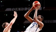 Kevin Durant, in white, fades away with an Australian hand reaching to block his jumper