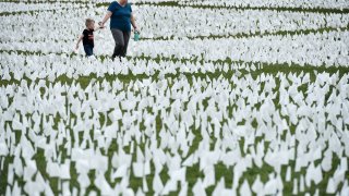 A woman and child walk through a field of white flags on the Mall near the Washington Monument in Washington, DC on September 16, 2021.