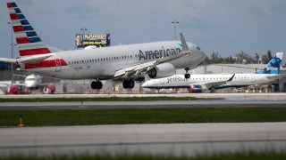 An American Airlines plane lands on a runway near a parked JetBlue plane at the Fort Lauderdale-Hollywood International Airport on July 16, 2020 in Fort Lauderdale, Florida.