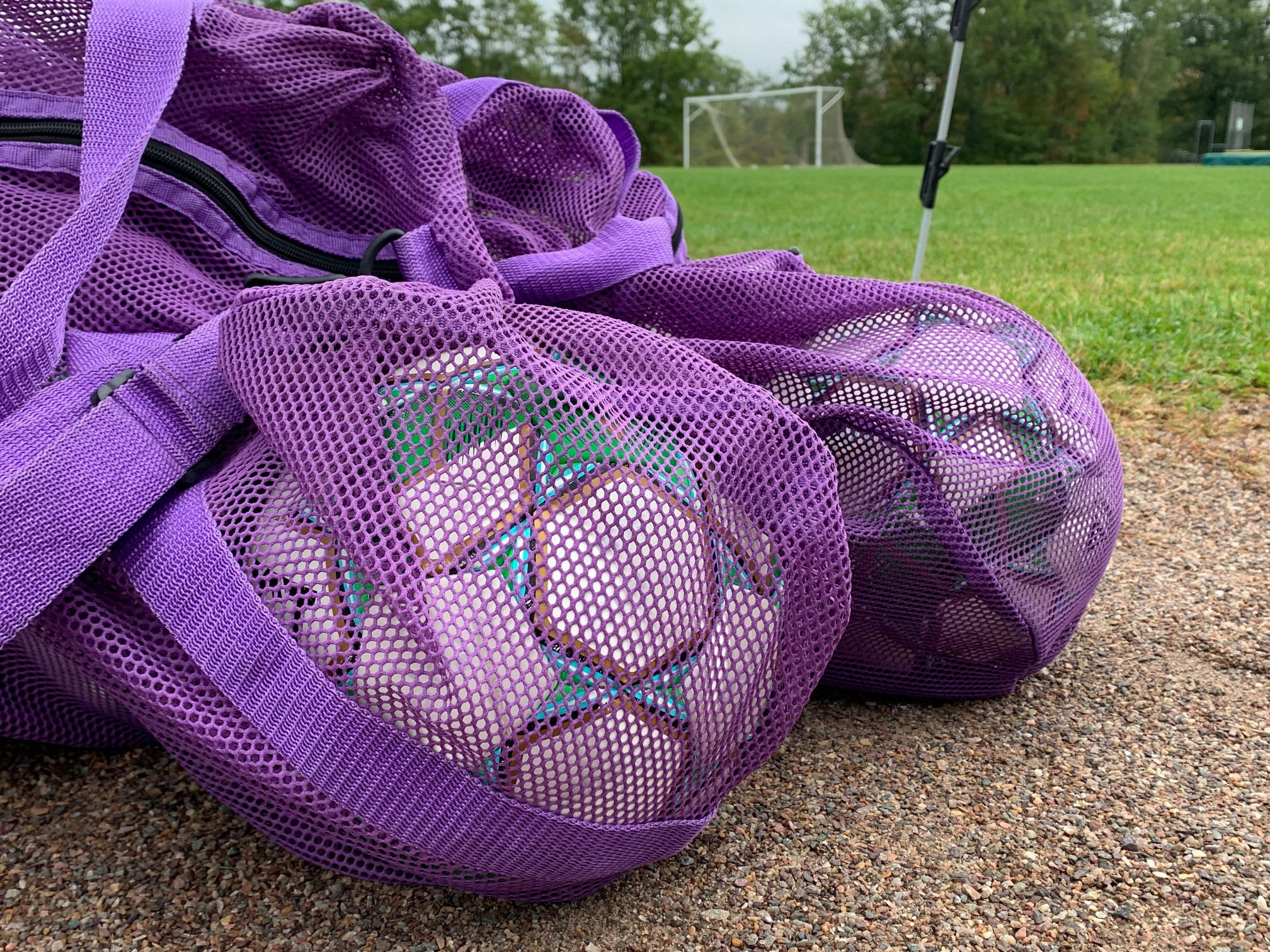 A bag containing soccer balls next to a soccer field