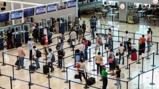 tourists wait to check in at the airport in Cancun, Mexico