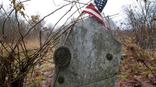 This Dec. 10, 2019, photo shows the gravestone of Revolutionary War soldier William Haven who is buried in a cemetery in Weybridge, Vt., near the edge of an eroding river bank. Rising seas, erosion and flooding from worsening storms that some scientists believe are caused by climate change are putting some older graveyards across the country at risk.
