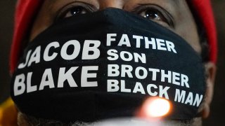 Jacob Blake Sr., father of Jacob Blake, holds a candle at a rally Monday, Jan. 4, 2021, in Kenosha, Wis.