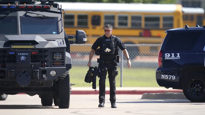 A law enforcement officer walks in the parking lot of Timberview High School after a shooting inside the school in south Arlington, Texas, Wednesday, Oct. 6, 2021.