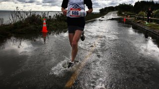 This 2011 file photo shows a man running through a flooded section of the Cape Cod Marathon.