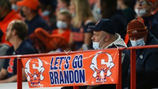 In this photo, a sign reading “Let’s go Brandon” is displayed on the railing in the first half of an NCAA college football game between Boston College and Syracuse in Syracuse, N.Y., Saturday, Oct. 30, 2021.