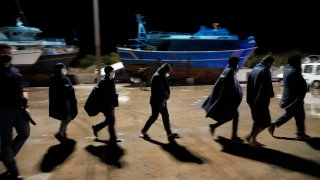 Migrants walk on the quay after disembarking in Roccella Jonica, Calabria region, southern Italy
