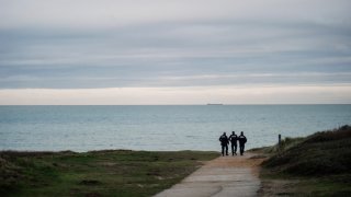 French police officers patrol on the beach in the searcher migrants in Wimereux, northern France, Wednesday, Nov.17, 2021. Several migrants died and others were injured Wednesday Nov.24, 2021 when their boat capsized off Calais in the English Channel as they tried to cross from France to Britain, authorities said. British and French authorities were searching the area using helicopters and coast guard vessels, according to the French maritime agency for the region.