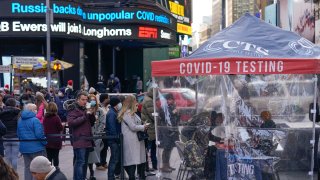 People wait in line at a COVID-19 testing site in Times Square, New York, Monday, Dec. 13, 2021. A mask mandate for shops and other indoor spaces in New York state took effect Monday as officials confront a surge in COVID-19 cases and hospitalizations.