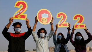 Indians, wearing face masks to help curb the spread of the coronavirus, hold cutouts to welcome 2022 on New Year’s Eve in Ahmedabad, India, Dec. 31, 2021.