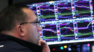 A trader looks at price monitors as he works on the floor at the New York Stock Exchange.