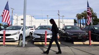 A pedestrian walks past a certified pre-owned car sales lot in Alhambra, California on January 12, 2022.