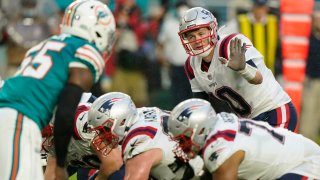 New England Patriots quarterback Mac Jones (10) directs his teammates during the first half of an NFL football game against the Miami Dolphins, Sunday, Jan. 9, 2022, in Miami Gardens, Fla.