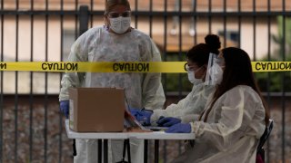 Healthcare workers work at a mobile COVID-19 testing site in Paramount, Calif., Wednesday, Jan. 12, 2022.
