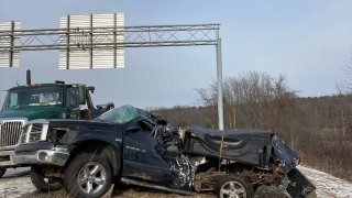 A destroyed pickup truck is pictured next to the interstate.