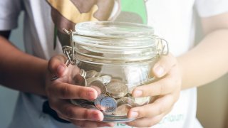 A photo of a child holding a jar of change.