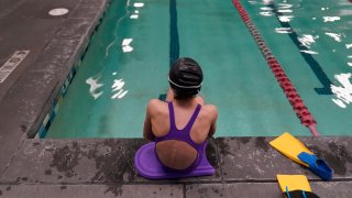 A swimmer sits on edge of a pool.