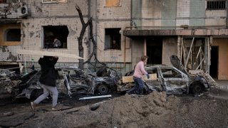 People carry wooden boards to cover the windows of a building damaged by a bombing the previous day in Kyiv, Ukraine, Monday, March 21, 2022. As Russia intensified its effort to pound Mariupol into submission, its ground offensive in other parts of Ukraine has become bogged down. Western officials and analysts say the conflict is turning into a grinding war of attrition, with Russia bombarding cities.