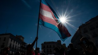 Demonstrator waving the Trans flag attends a protest where