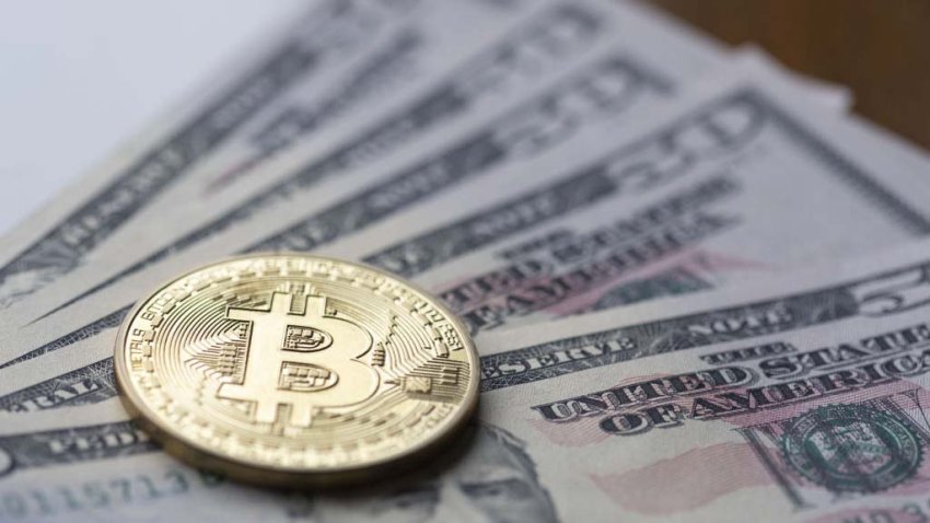 A Bitcoin token on top of U.S. dollars arranged in Montreal, Quebec, Canada, on Wednesday, March 2, 2022. Bitcoin was little changed after rallying more than 16% over the past two days as the possibility of expanding sanctions was raised to prevent Russians from using cryptocurrencies to circumvent restrictions. Photographer: Christinne Muschi/Bloomberg via Getty Images