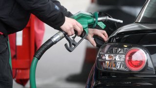A person using a petrol pump at a petrol station in London.
