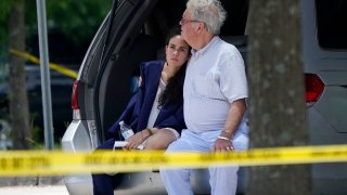 A man comforts a young woman wearing a graduation gown within the crime scene of a shooting at Xavier University in New Orleans, Tuesday, May 31, 2022.