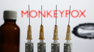 Medical syringes and a bottle are seen with ‘Monkeypox’ sign and monkeypox illustrative model displayed on a screen in the background in this illustration photo taken in Krakow, Poland on May 26, 2022. (Photo by Jakub Porzycki/NurPhoto via Getty Images)