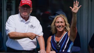 Rep. Marjorie Taylor Greene, R-Ga., waves while former President Donald Trump points to her