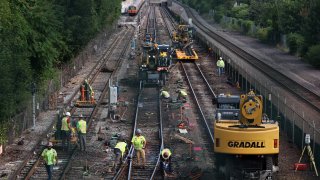 Crews work on the tracks at the Wellington T station in Medford, Massachusetts, on Saturday, Aug. 20, 2022, during the first full day of the train line's 30-day shutdown.