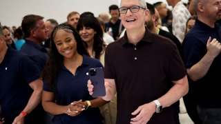 Apple CEO Tim Cook reacts as he holds the new iPhone 14 at an Apple event at their headquarters in Cupertino, California, September 7, 2022.