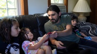 Mohammad Walizada, center right, who fled Afghanistan with his family, sits with three of his children