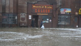 Two men walk through rushing water on Front Street, just a half block from the Bering Sea, in Nome, Alaska