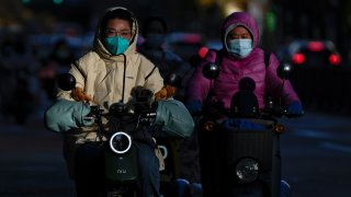 Motorists wearing face masks ride their electric-powered scooters on a street during the morning rush hour in Beijing, Monday, Oct. 31, 2022.