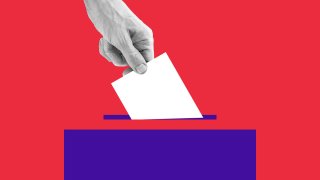 A human drops a ballot into a ballot box.