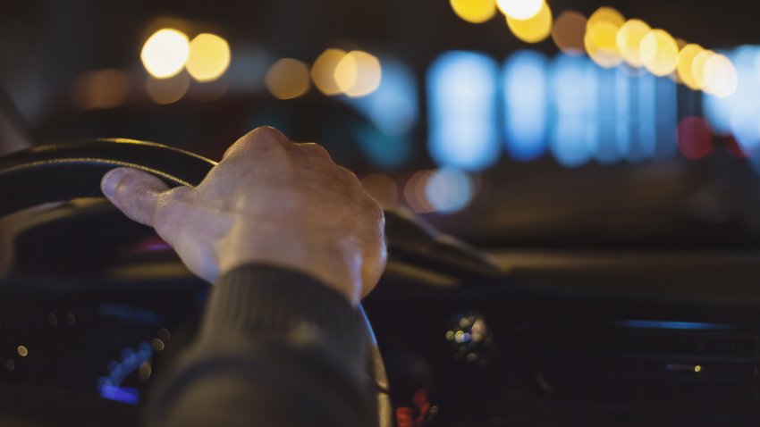 Hand on steering wheel at night.